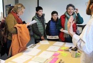 A family standing around a table with coloured pieces of paper and other stationery